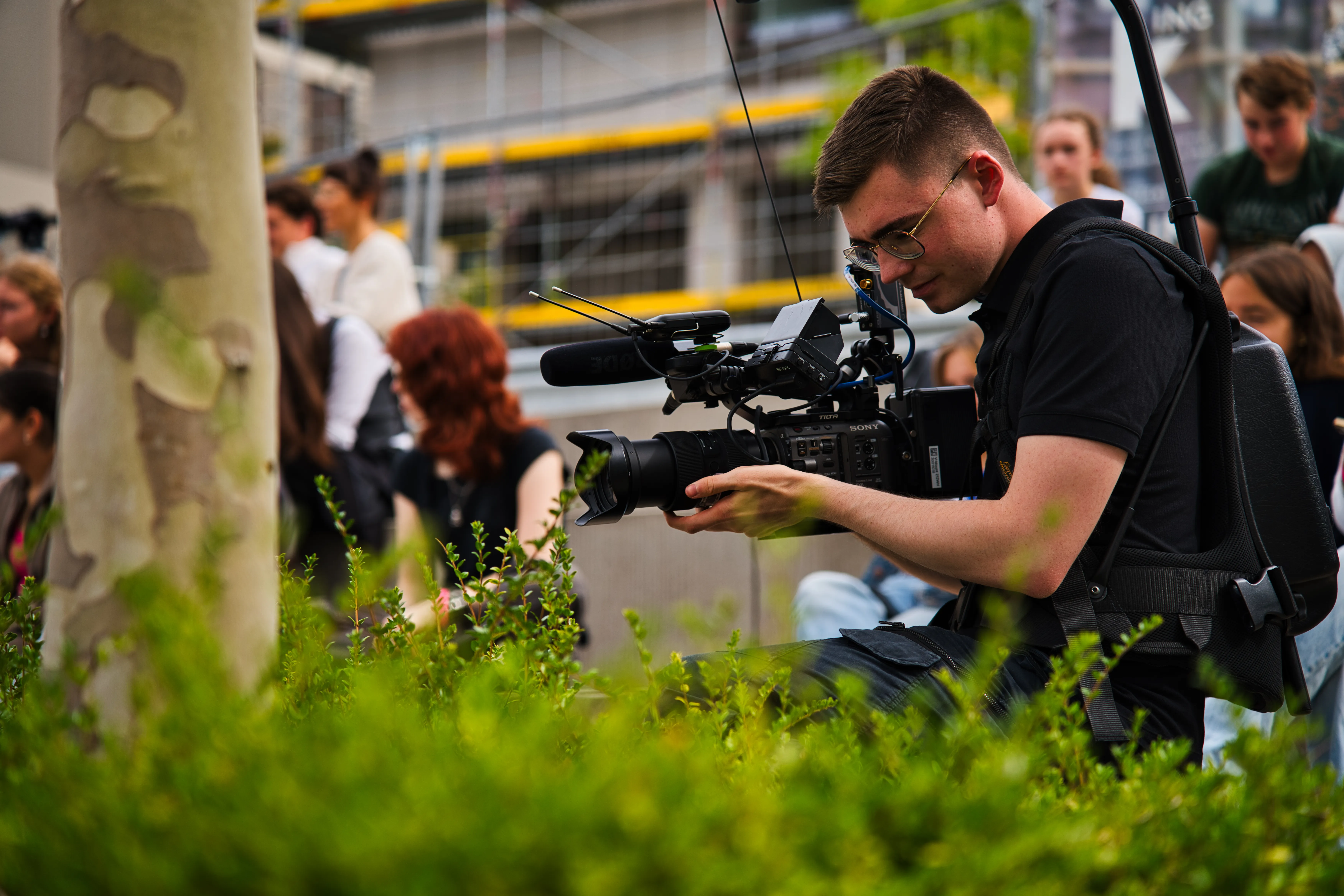 Mensch mit mobiler Kamera, der das Geschehen auf der Bühne filmt.
